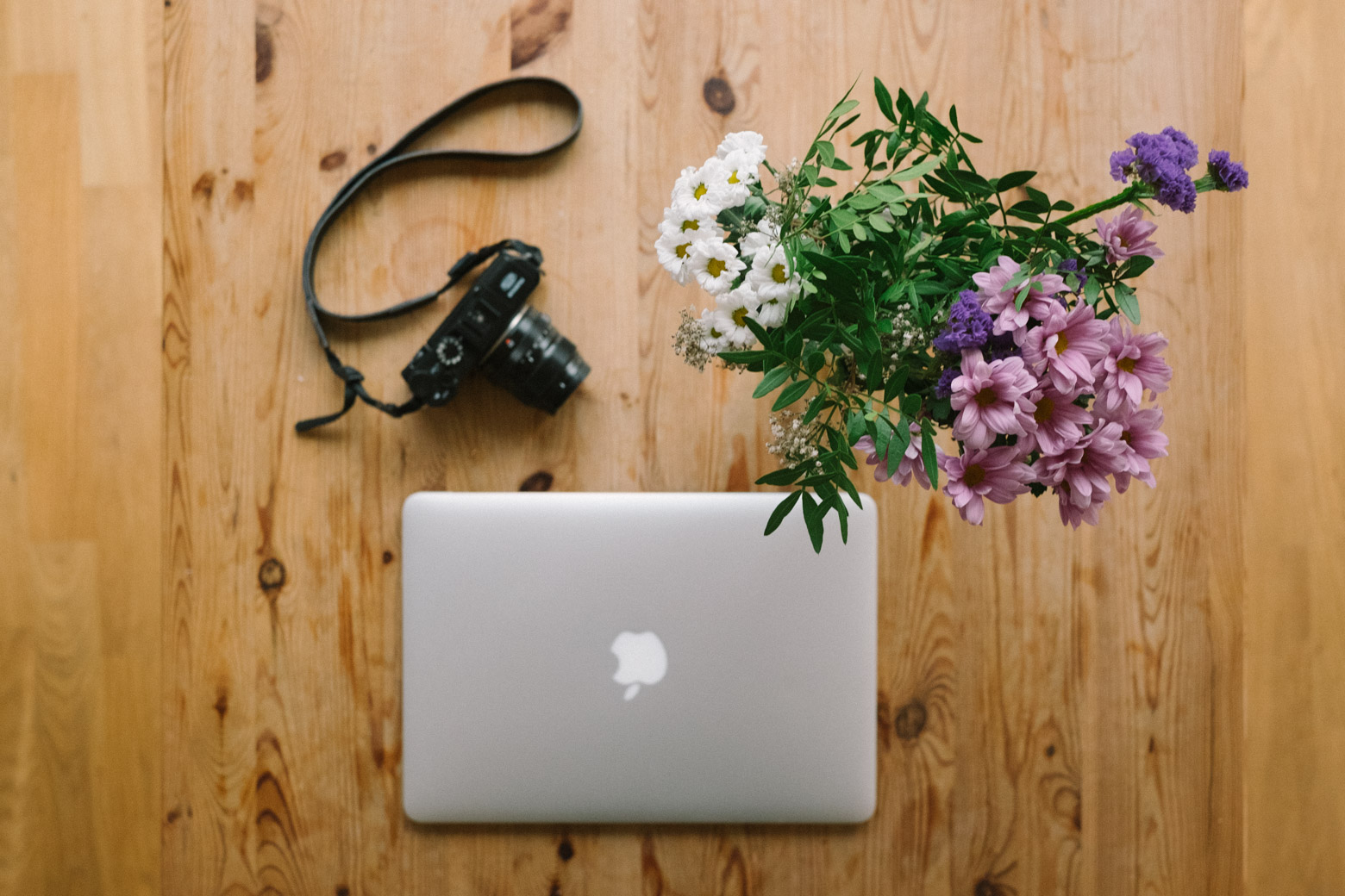 A computer next to flowers and coffee