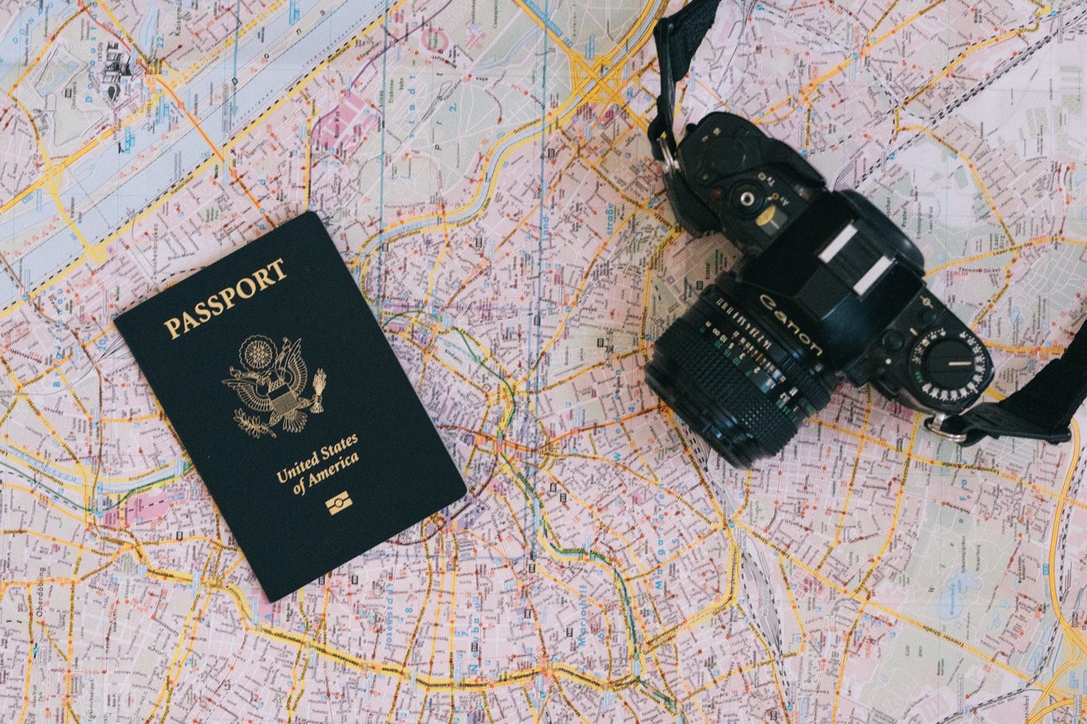 Passport, film camera, and an ipad on a map
